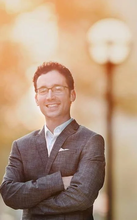 a photo of ypsilanti realtor Alexander Munro posing with arms crossed in business attire