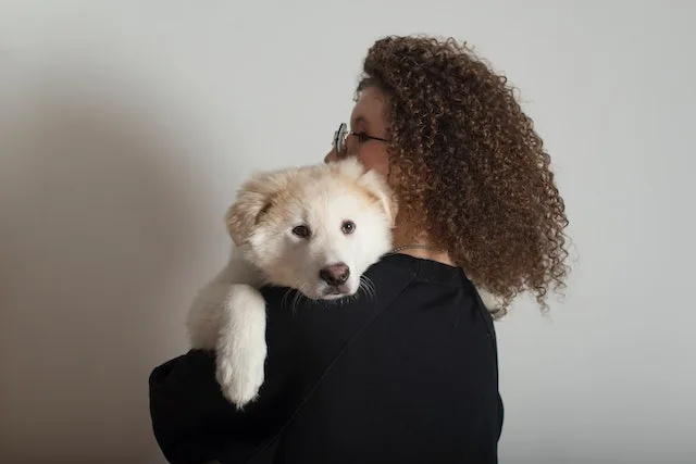 a woman holding a puppy who is probably thinking it's time to sell the condo and buy a home with a yard