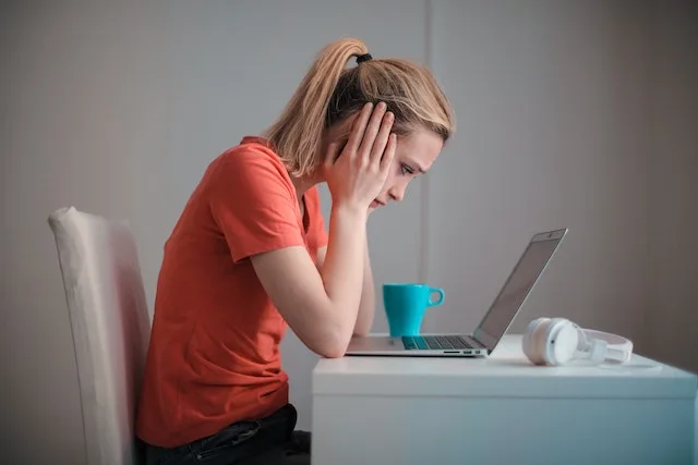 a woman covering hear ears at her computer because of noisy condo neighbors